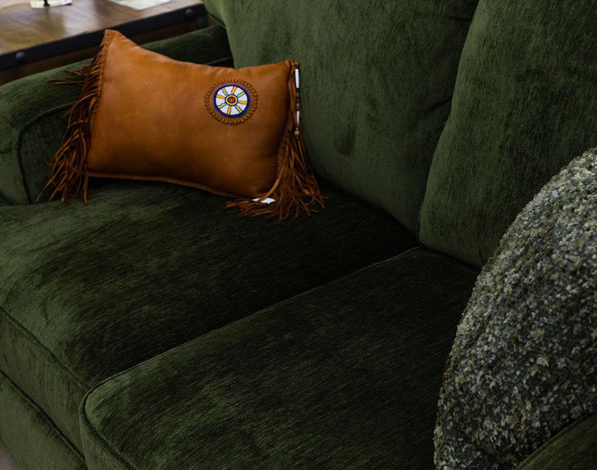 Green velvet sofa with a leather pillow